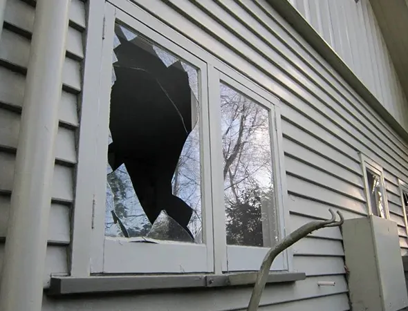 A broken window with cracked or shattered glass, posing a safety concern and requiring prompt repair or replacement.